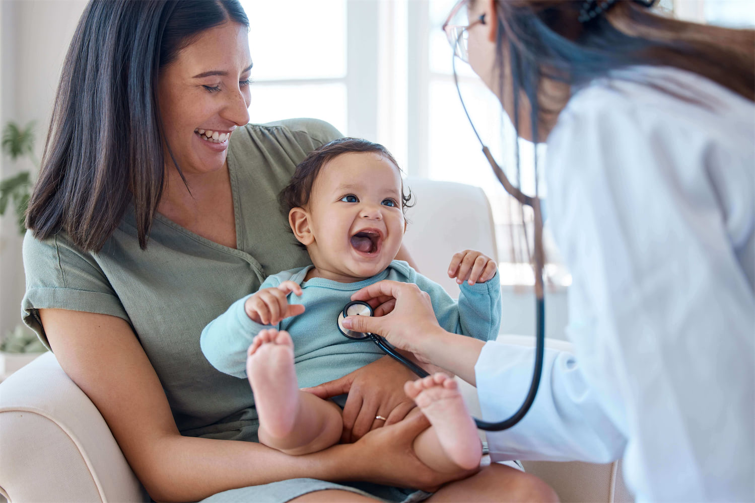 A mother holds her smiling baby during a routine pediatric checkup