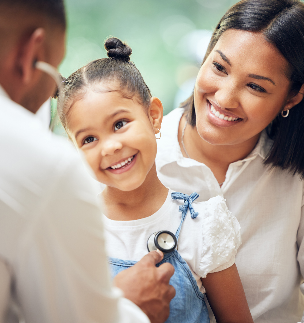 A pediatric provider listens to a young girl's breathing while her mother holds her