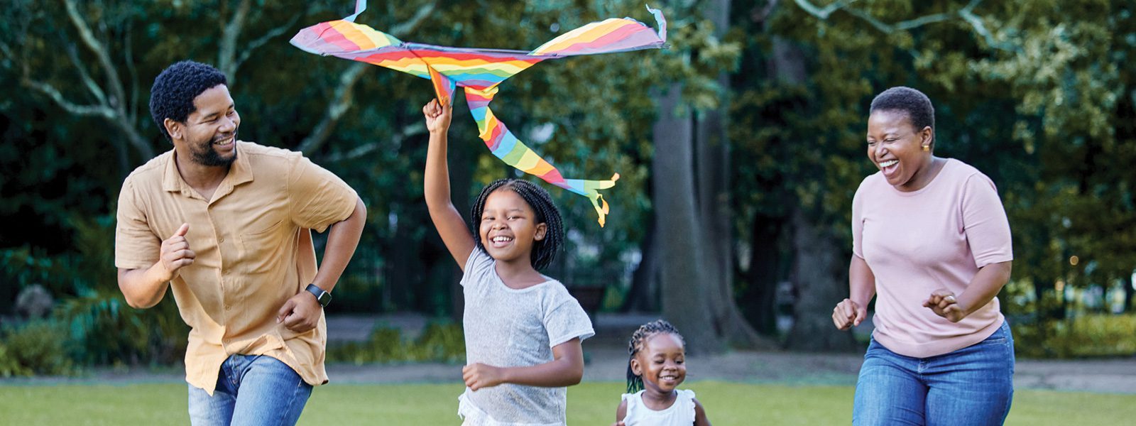 Kids running with parents flying a kite